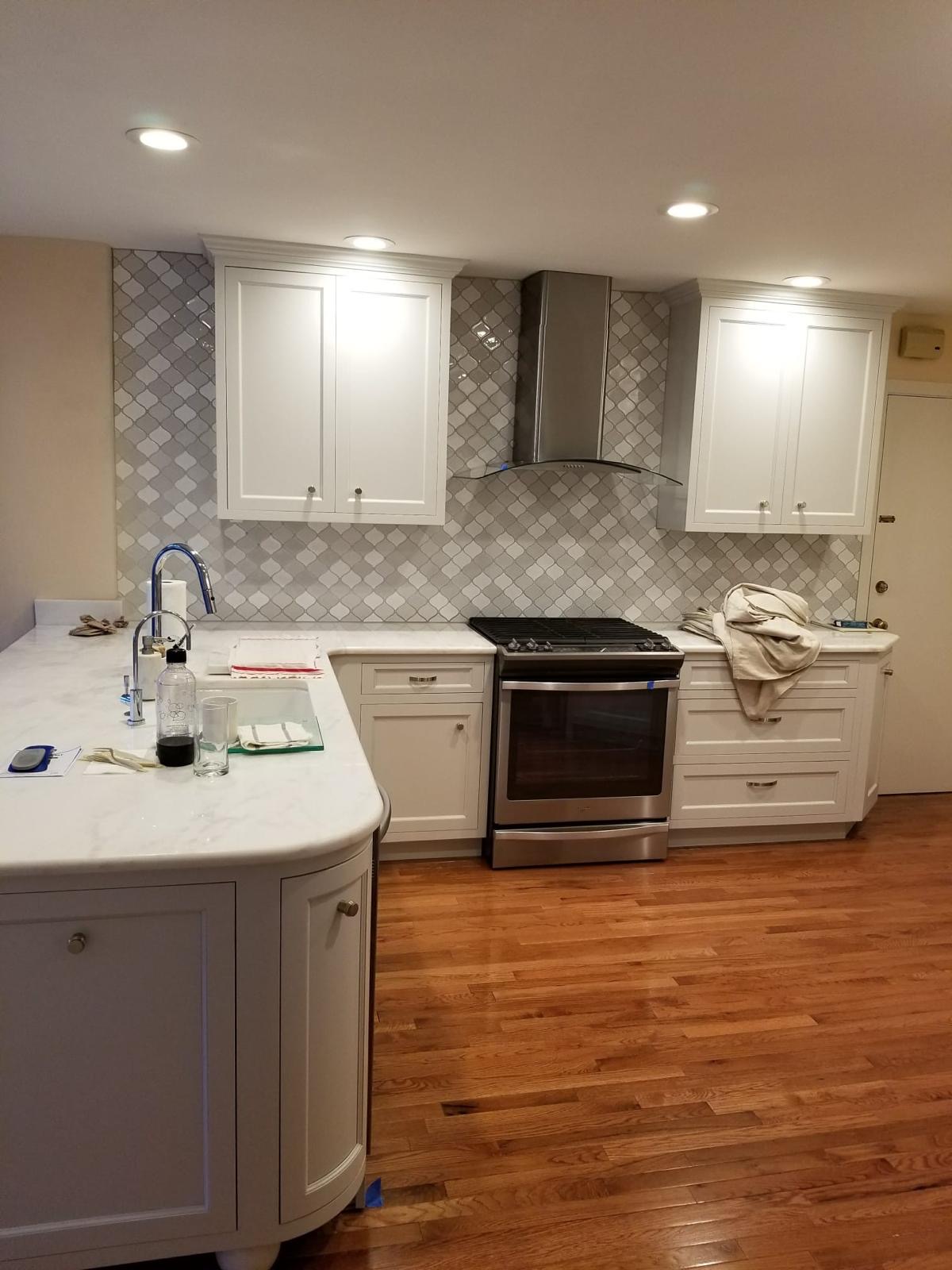 Kitchen with marble countertops, arabesque tile backsplash and refinished hardwood flooring