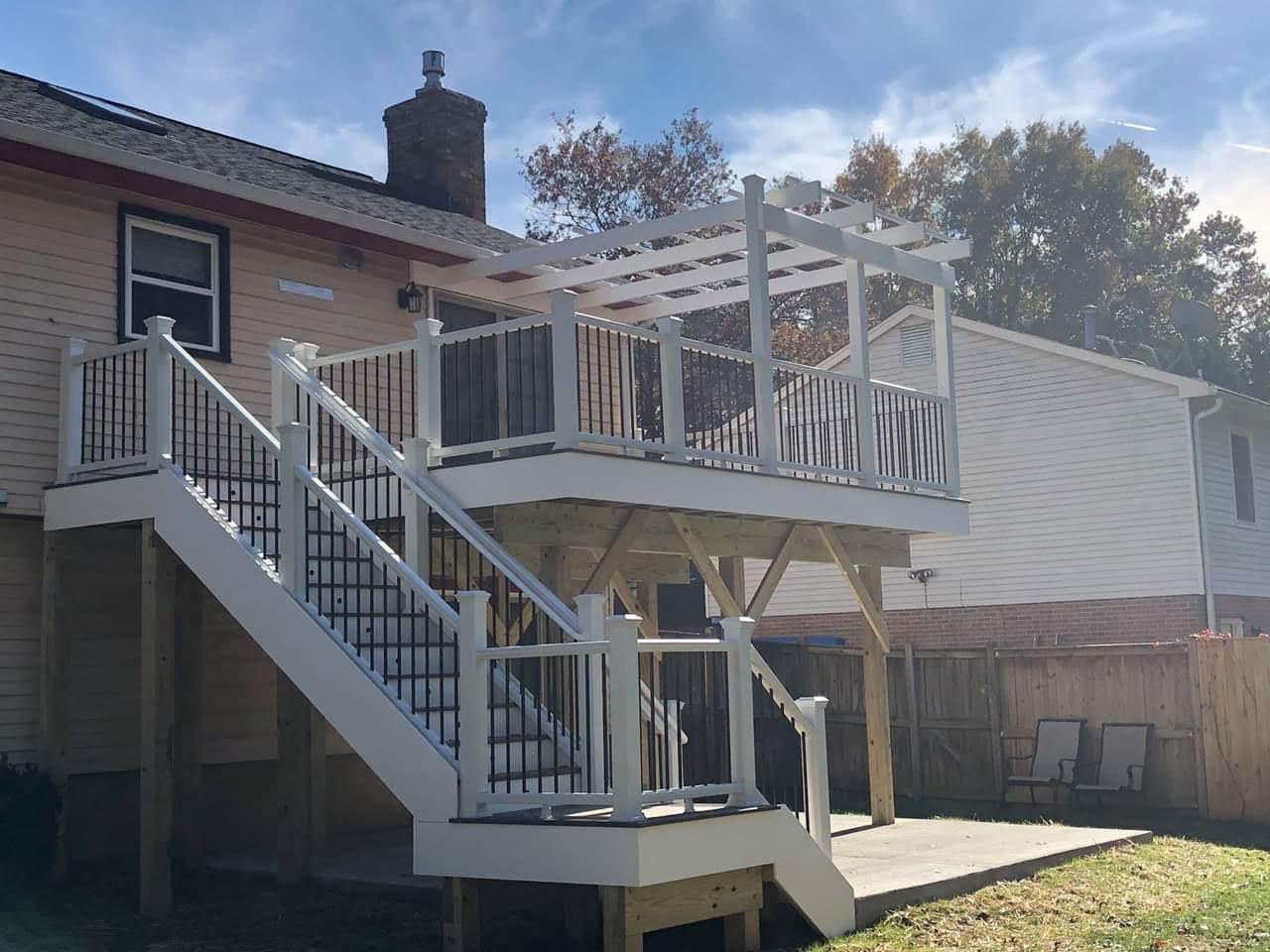 Elevated deck with white railings, stairs and pergola at the rear of a home