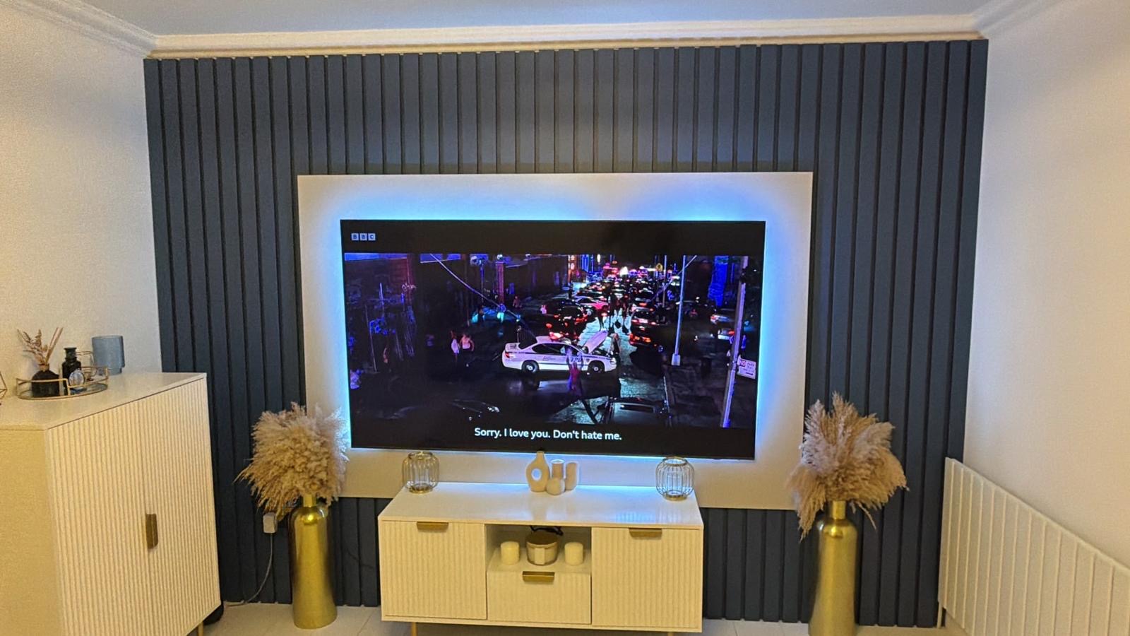 Slat accent wall with backlit television feature in a living room