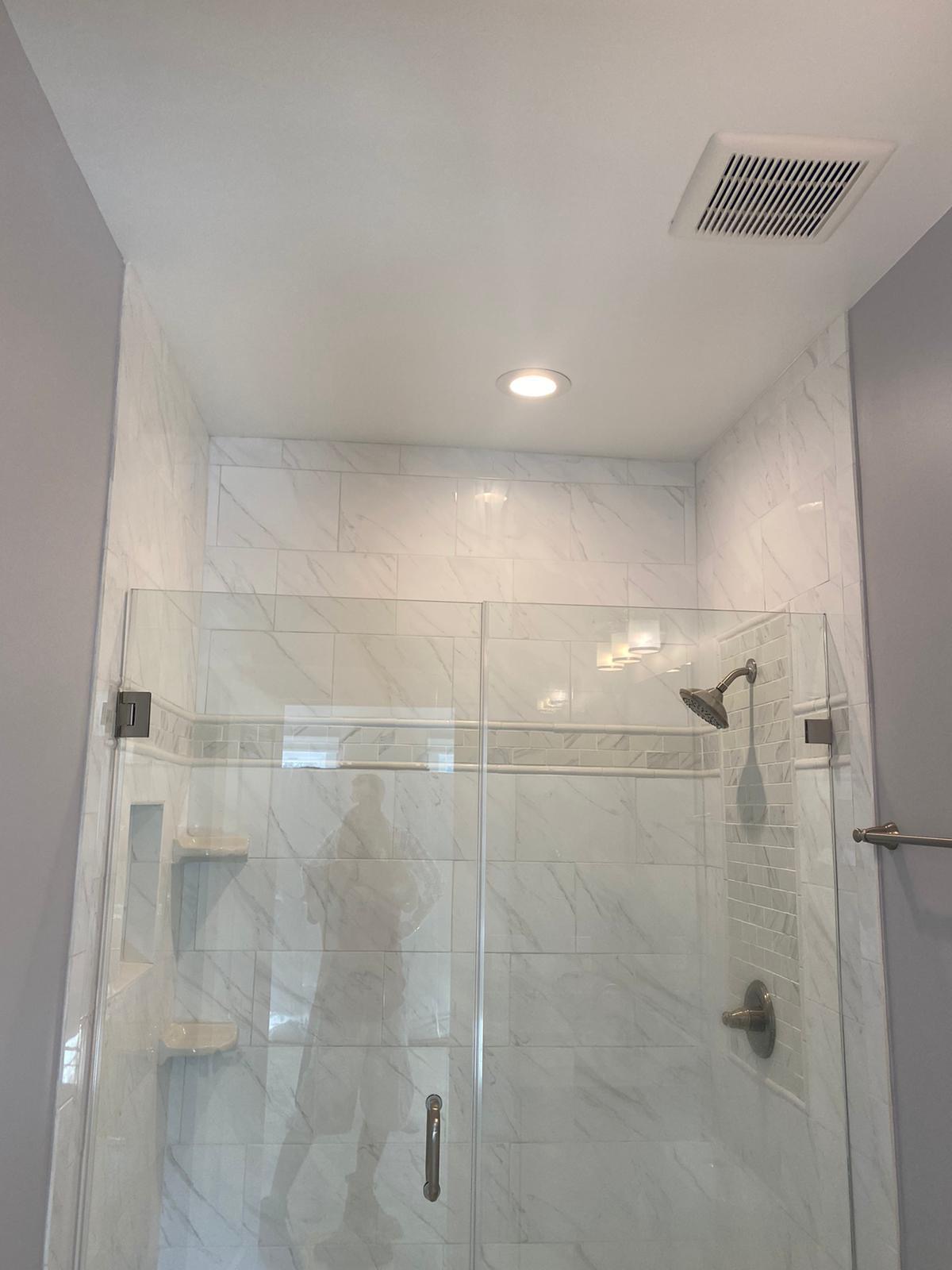 Bathroom remodel with marble-look tile shower and frameless glass door