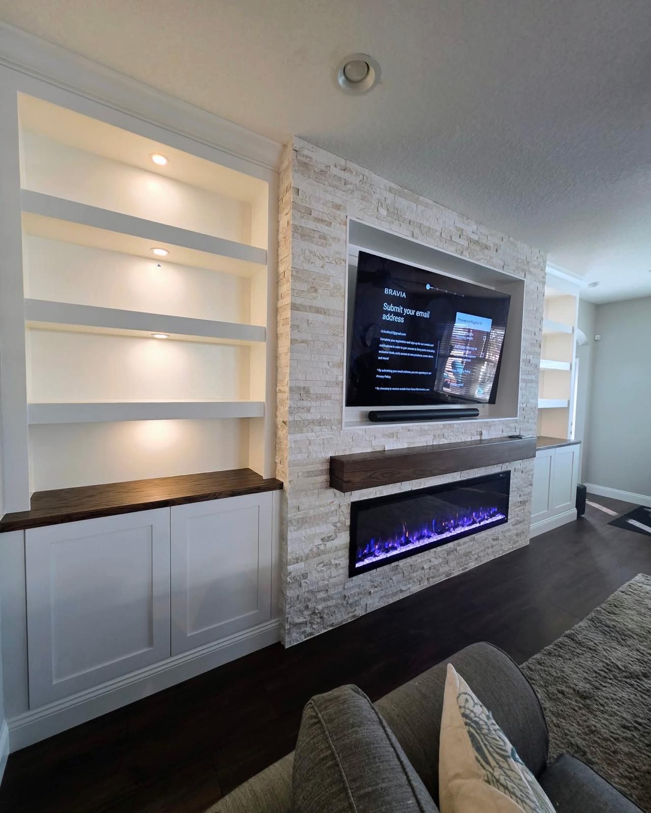 Custom built-in shelving and stone fireplace wall with floating mantel