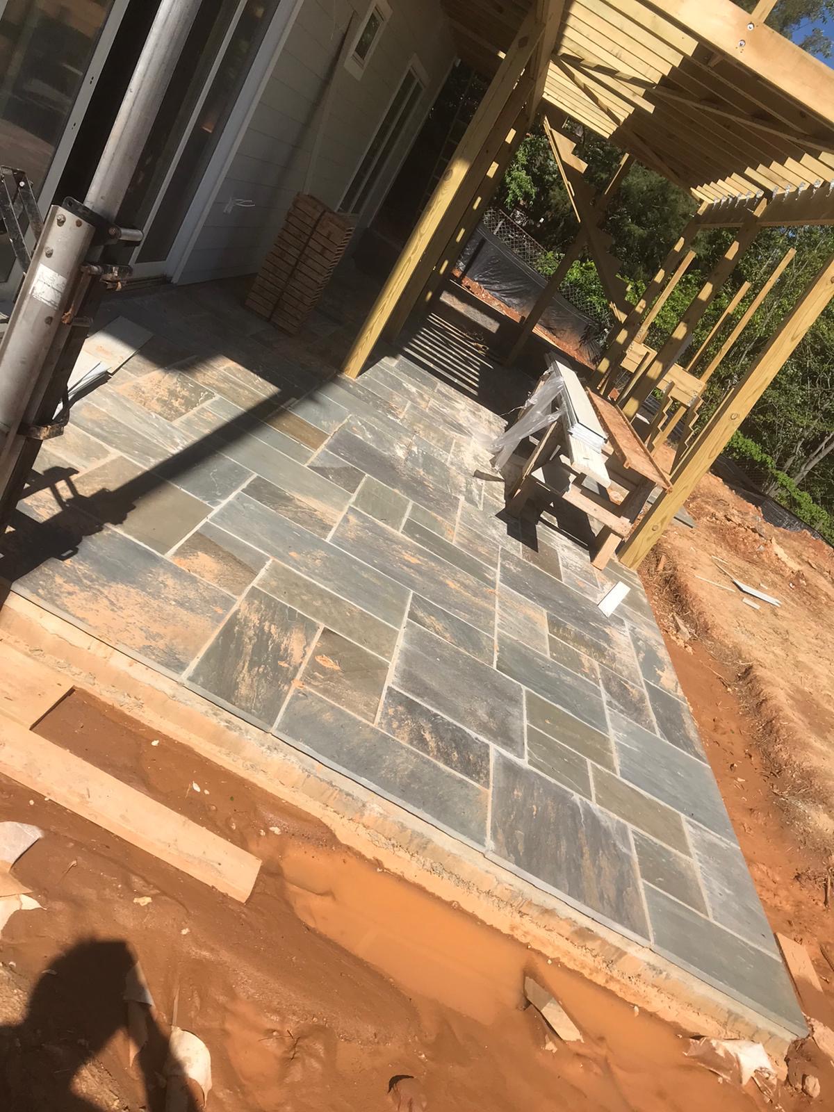 Natural stone patio installation with framed pergola structure above