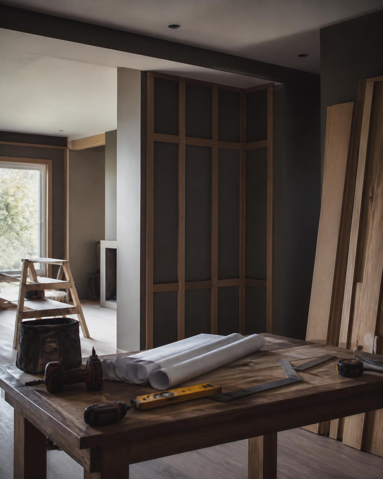 Home interior under renovation with carpentry trim work, tools and project plans on a work table